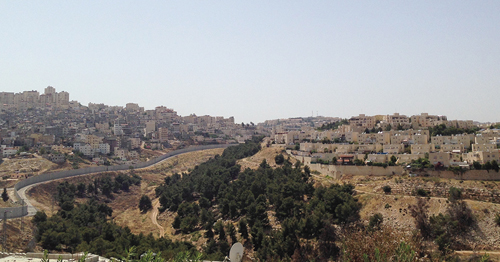 The Annexation Wall prohibits the expansion of Shufat Refugee Camp (left), while providing land for the expansion of the illegal settlement of Pisgat Ze’ev (right). Photo by Marya Farah.